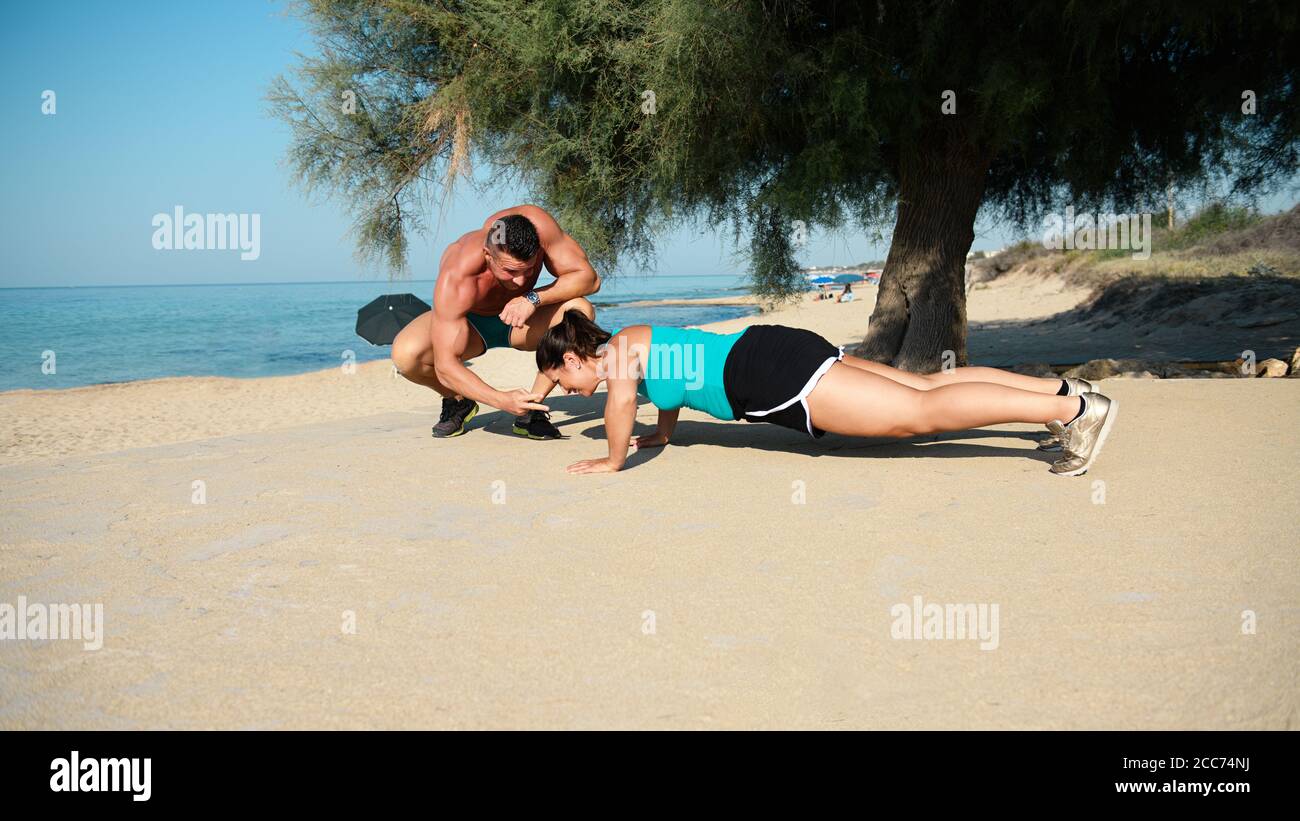 Trainer gibt Anweisungen eine fit junge Frau Ausübung Push-up Im Sommer am Strand Stockfoto