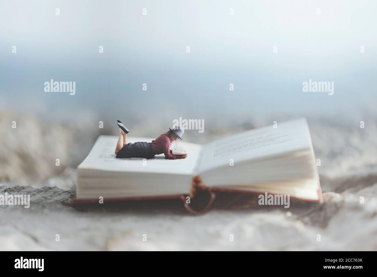 Frau liest ihr Buch, das auf einem riesigen Buch liegt Stockfoto