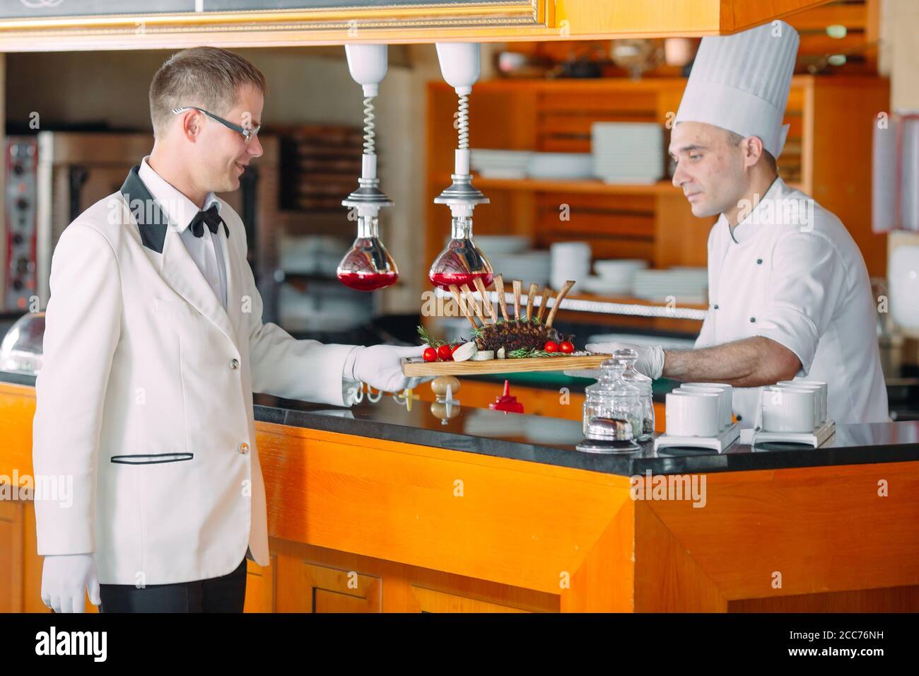 Der Koch leitet die Kellner das fertige Gericht. Lammrippchen. Stockfoto
