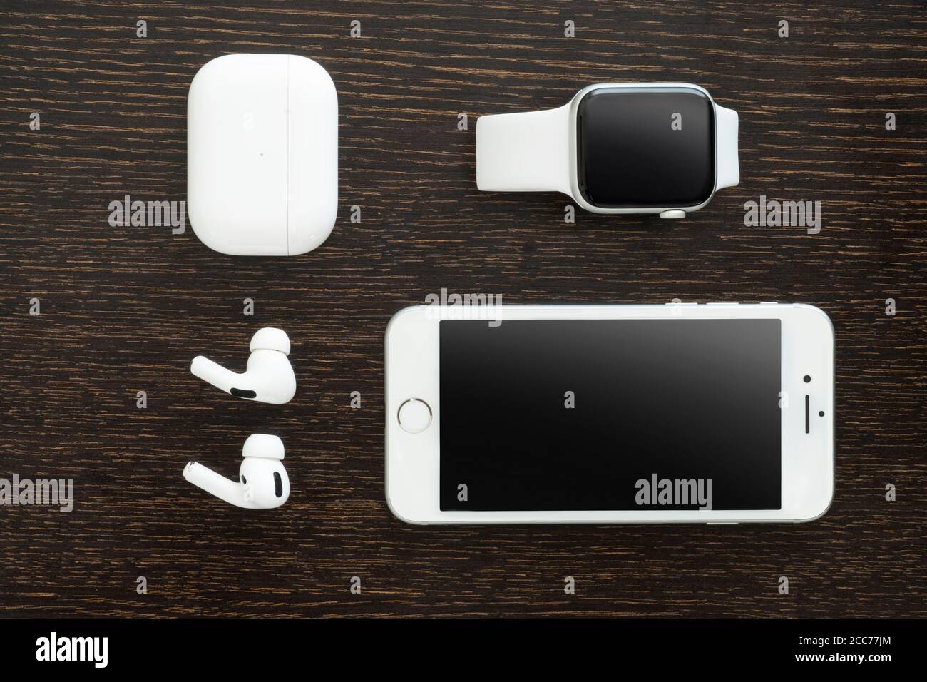 Izmir, Türkei - 7. August 2020: Nahaufnahme des weißen iPhone 8, der Apple Watch 5 und des Air Pods Pro auf einem Holzboden. Stockfoto