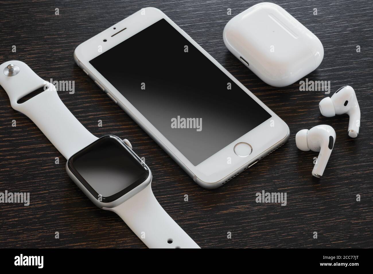 Izmir, Türkei - 7. August 2020: Nahaufnahme des weißen iPhone 8, der Apple Watch 5 und des Air Pods Pro auf einem Holzboden. Stockfoto