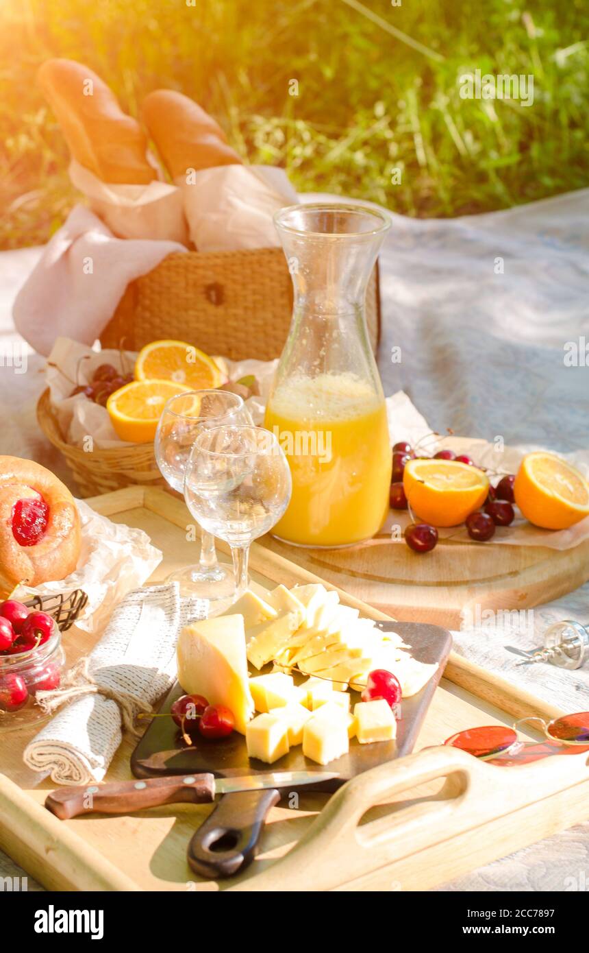 Romantisches Picknick im Park auf dem Rasen. Käse, Obst, Brot, Saft und Snacks auf der Decke Stockfoto