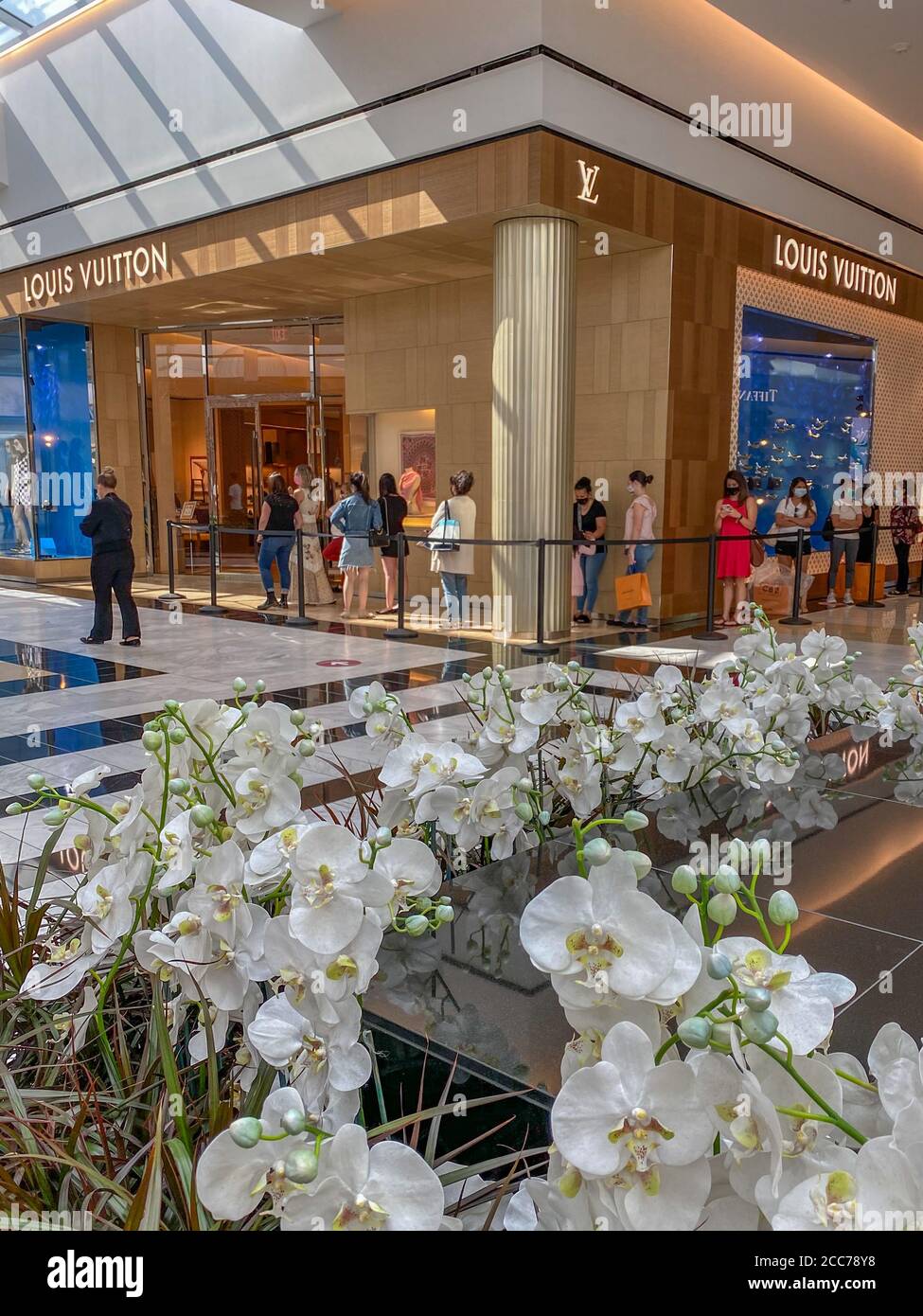 Im Louis Vuitton Store in der King of Prussia Mall in der Nähe von Philadelphia, PA, warten maskierte Käufer in der Schlange - gesellige Geschäfte Stockfoto