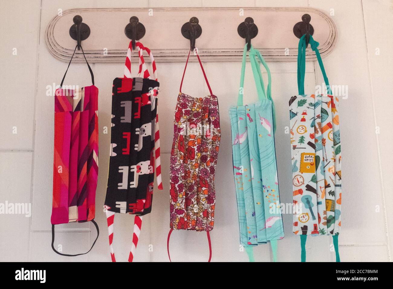 Gruppe von fünf gemusterten niedlichen Masken hängen an Haken Stockfoto