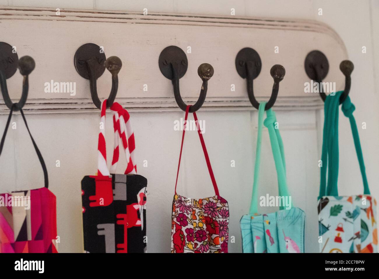 Gruppe von fünf gemusterten niedlichen Masken hängen an Haken Stockfoto