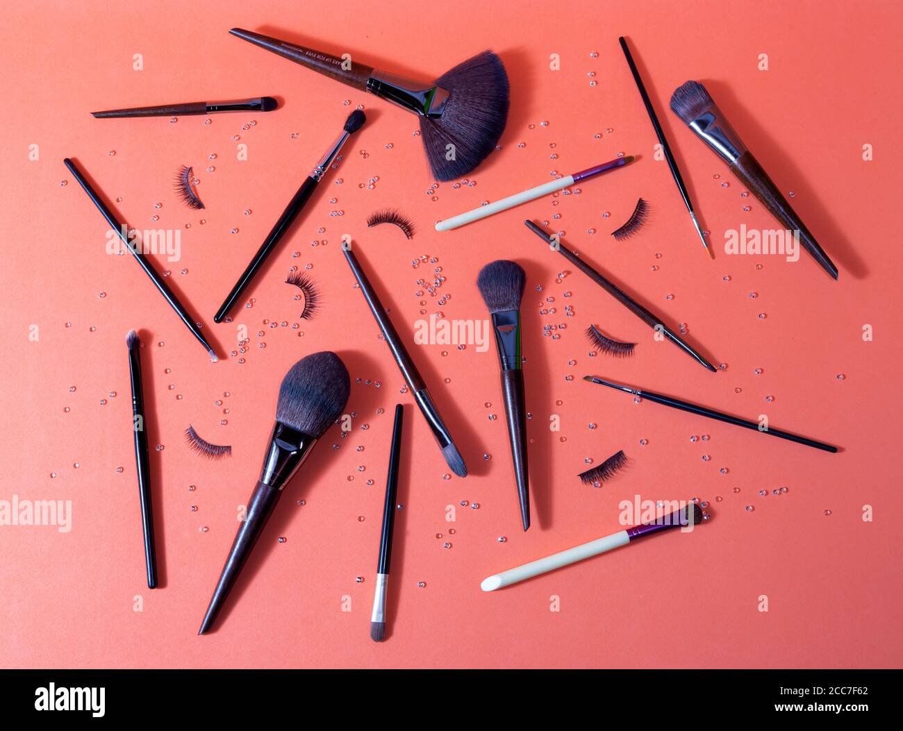 Orange Oberfläche, auf der es verschiedene Make-up Pinsel und Falsche Wimpern für den professionellen Einsatz Stockfoto