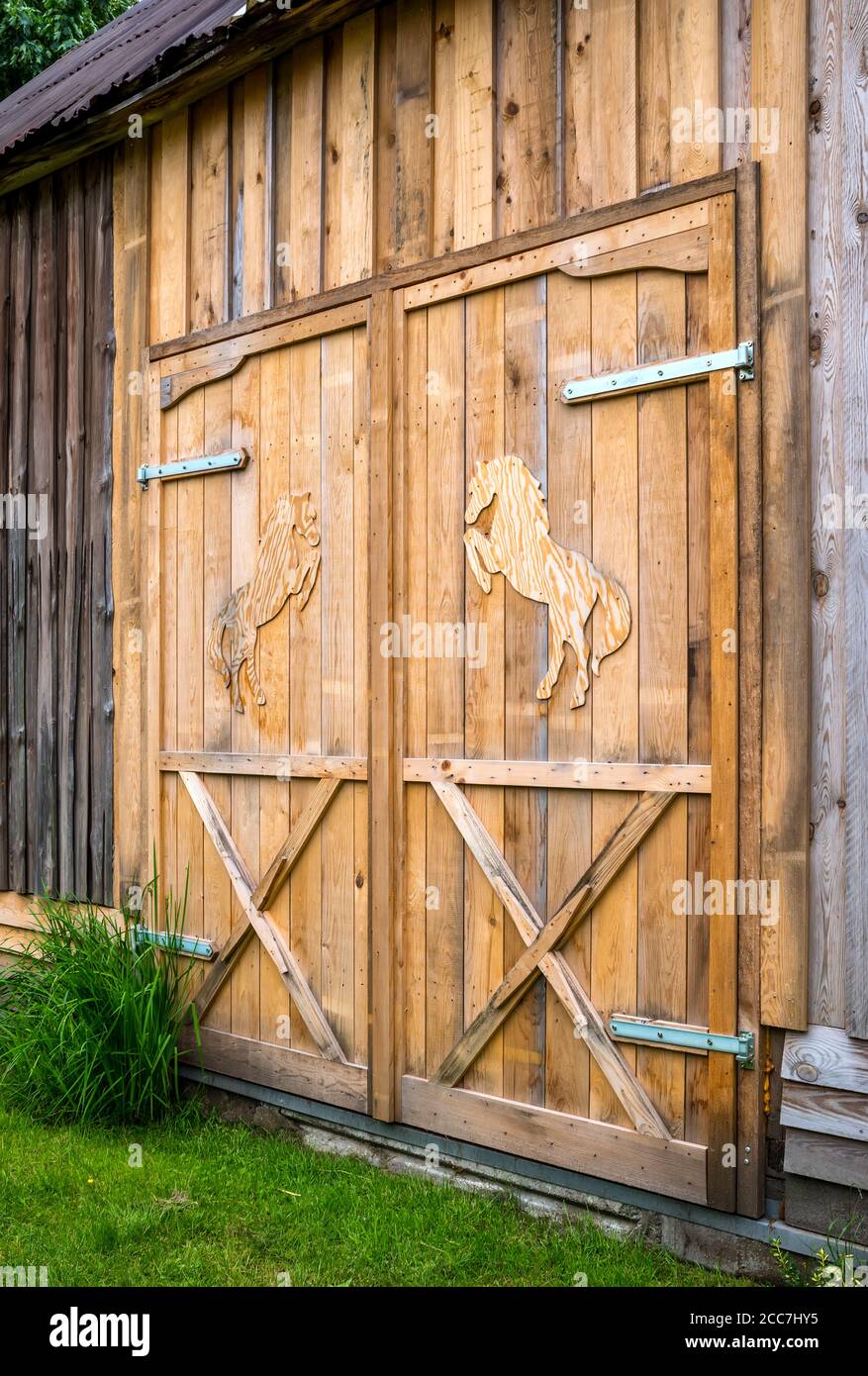 Original-Design, Holztüren mit Holzpferden. Geschlossener Eingang zum Stall. Stockfoto