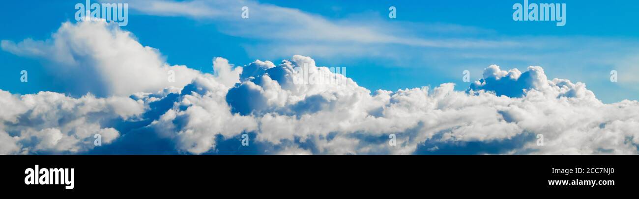 Schöne flauschige Wolken auf einem klaren blauen Himmel. Bannerformat. Hintergrund für Design. Stockfoto