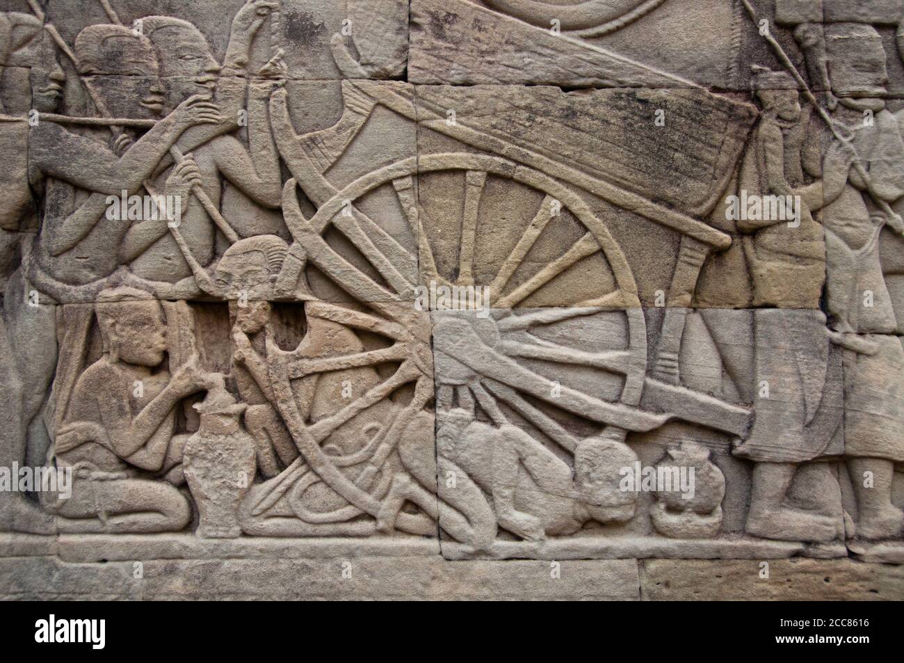 Kambodscha: Im Lager der Khmer-Armee bläst ein Mann auf ein Feuer, um neben einem Ochsenkarren, der Ostwand mit Flachrelief, dem südlichen Teil, dem Bayon, Angkor Thom, etwas zu kochen. Der Bayon war ursprünglich der offizielle Staatstempel des Mahayana Buddhistischen Königs Jayavarman VII. Das Bayon, im Zentrum von Angkor Thom (große Stadt), wurde im 12. Jahrhundert von König Jayavarman VII. Gegründet Angkor Thom, was ‘die große Stadt’ bedeutet, liegt eine Meile nördlich von Angkor Wat. Es wurde im späten 12. Jahrhundert CE von König Jayavarman VII. Gebaut Stockfoto