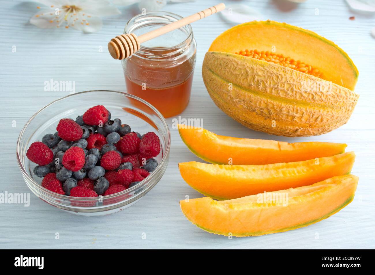 High-Angle-Ansicht der Schüssel mit Beerenfrüchten und in Scheiben geschnitten Orangefarbene Melone Stockfoto