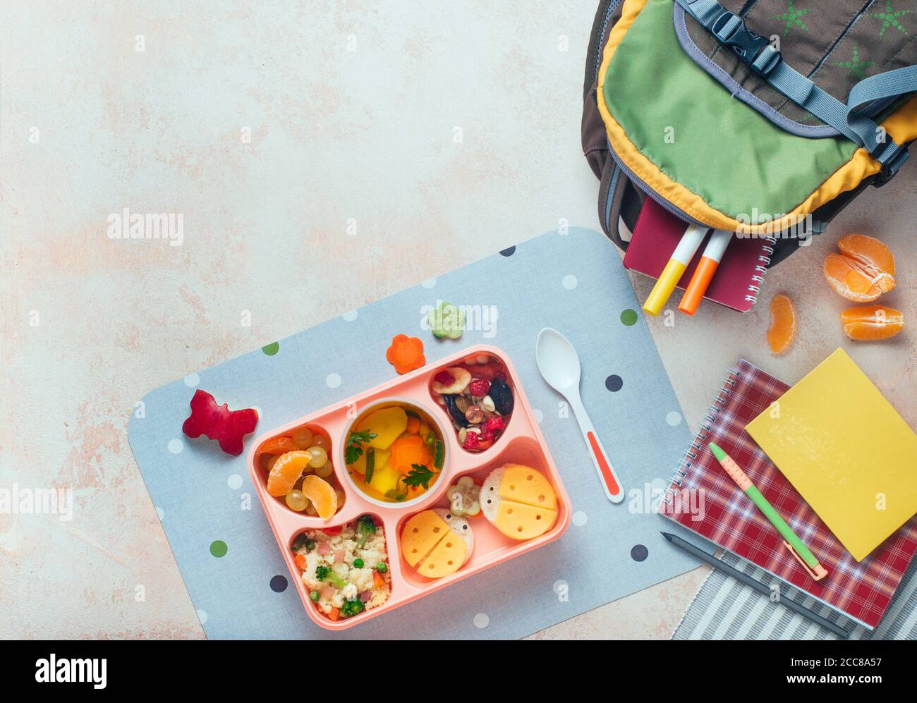 Lunchbox mit Gemüsesuppe, Couscous-Salat und lustige Sandwiches in der Nähe von Rucksack Stockfoto