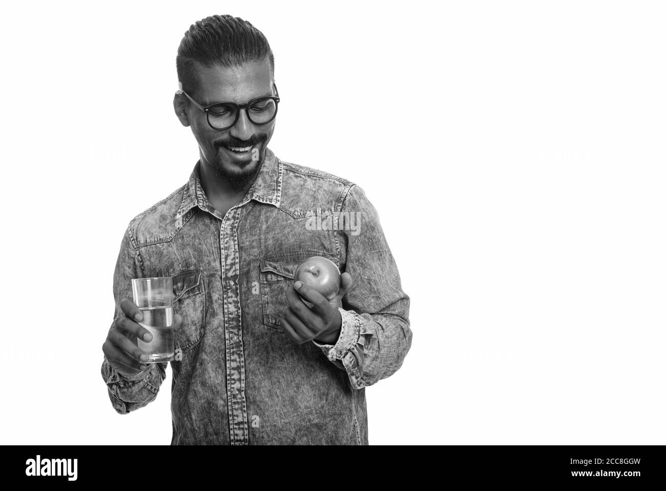 Junge glücklich indischen Mann hält roten Apfel und Glas Wasser Stockfoto