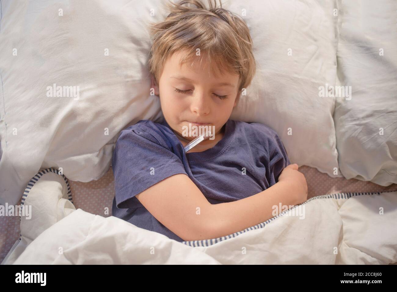 Kind krank im Bett mit Fieber und Thermometer Stockfoto