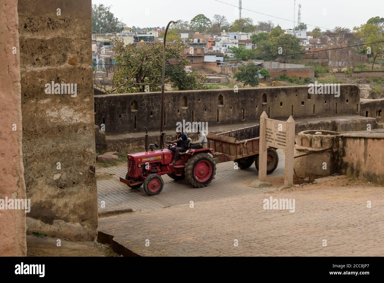 Orchha, Madhya Pradesh, Indien - März 2019: Zwei indische Männer fahren einen Traktor auf einer Straße durch die alten Mauern der historischen Festung im Dorf O Stockfoto