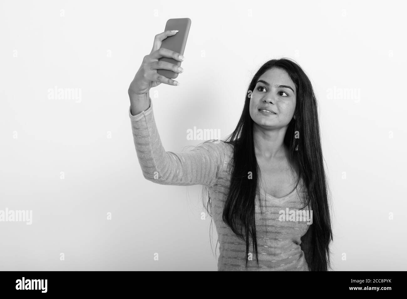 Studio shot der jungen indischen Glücklich lächelnde Frau während der Einnahme von selfie Bild mit Handy vor weißem Hintergrund Stockfoto
