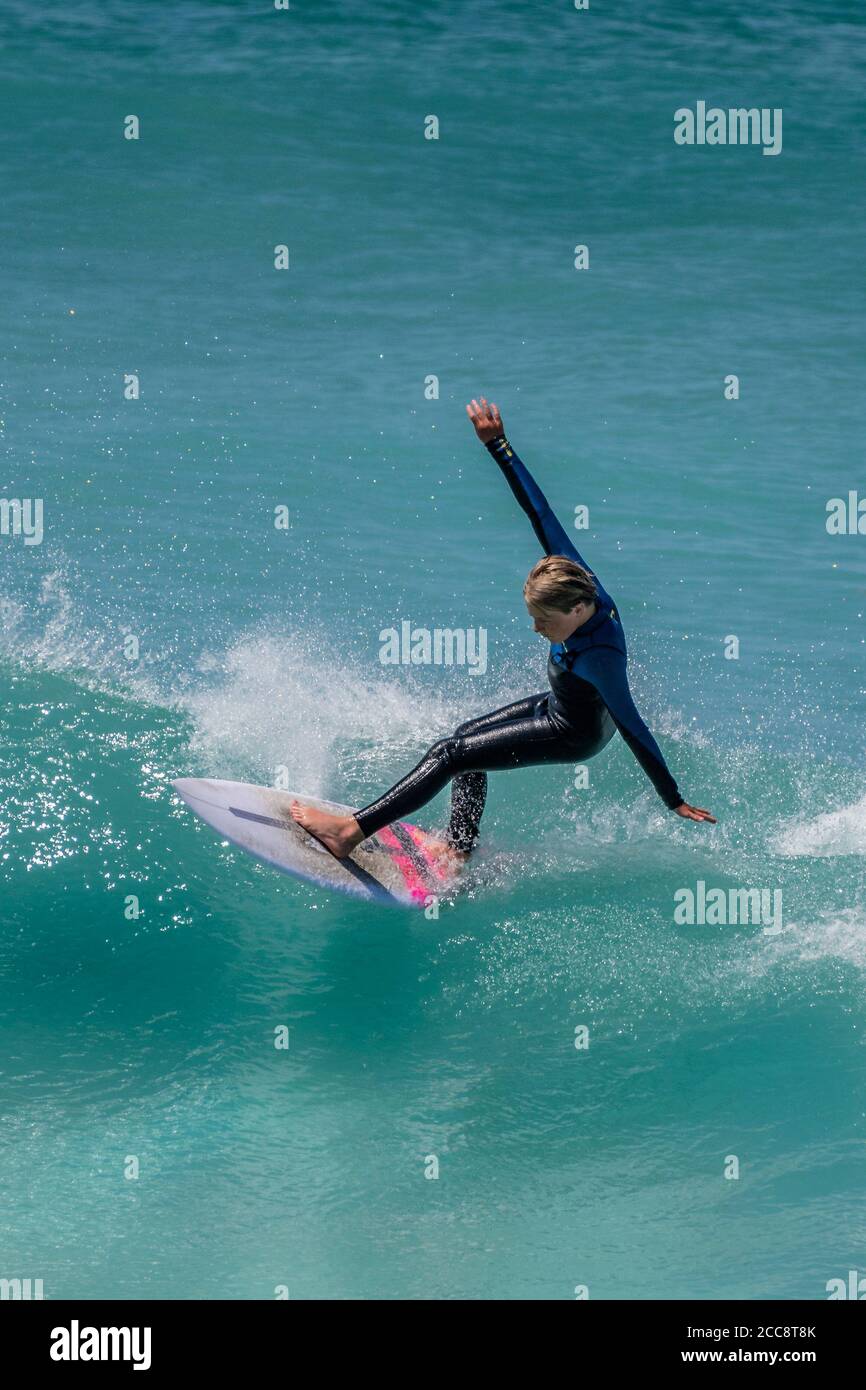 Spektakuläre Action, während ein junger Surfer im Teenageralter eine Welle im Fistral in Newquay in Cornwall reitet. Stockfoto
