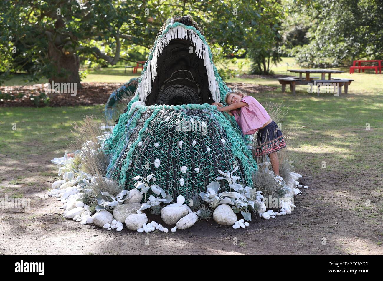 Die fünfjährige Sylvie Fodio Todd aus Lewes blickt auf die botanische Skulptur eines Buckelwals, der aus dem Orangery Lawn auftaucht, während er bis September 18 im Rahmen des Travel the World at Kew Festivals in den Royal Botanic Gardens in London zu sehen ist. Stockfoto