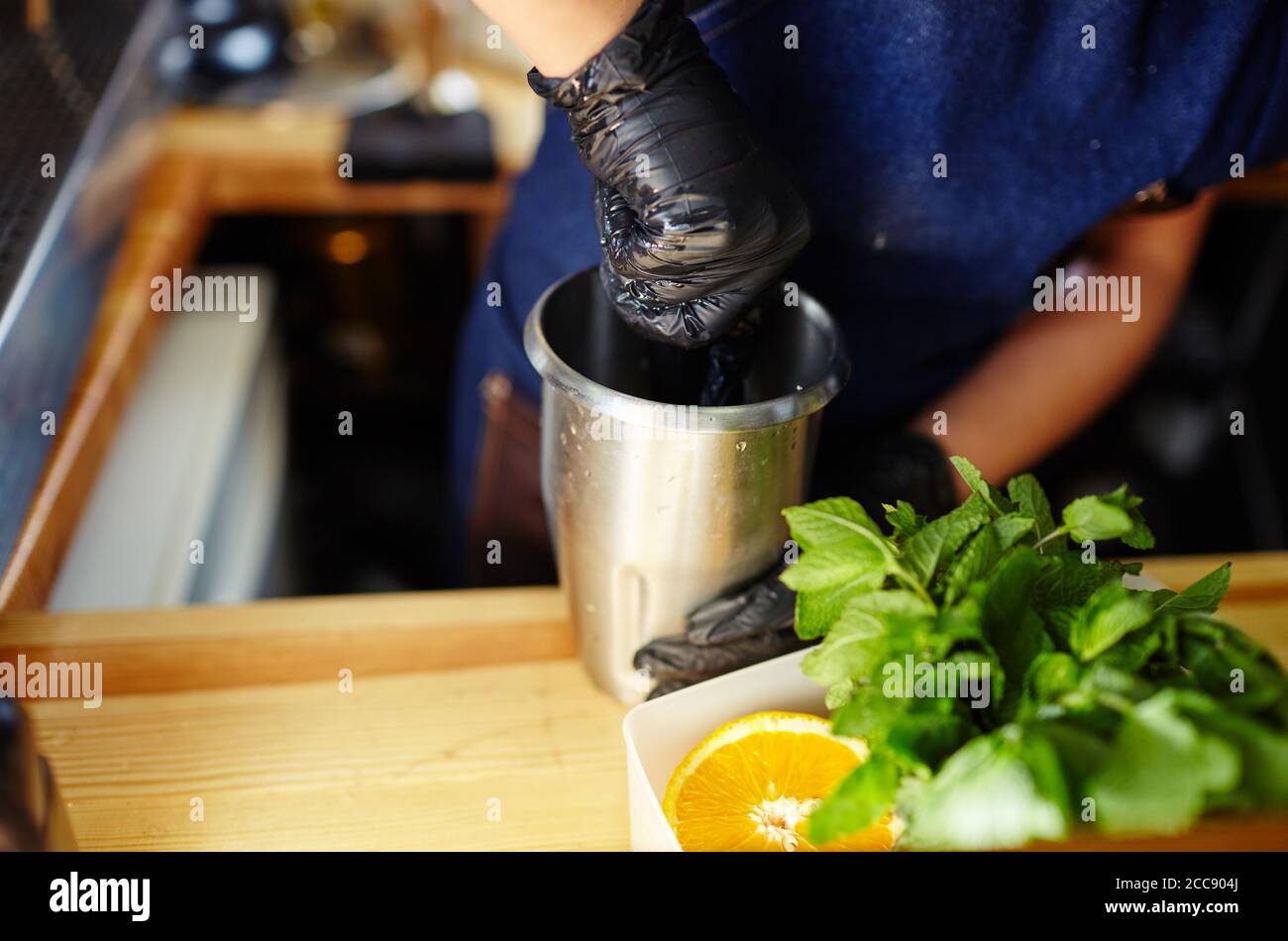 Barkeeper trägt medizinische Latexhandschuhe, macht Mojito Cocktail.Mint Blätter, Zutat für Getränke in der Bar Stockfoto