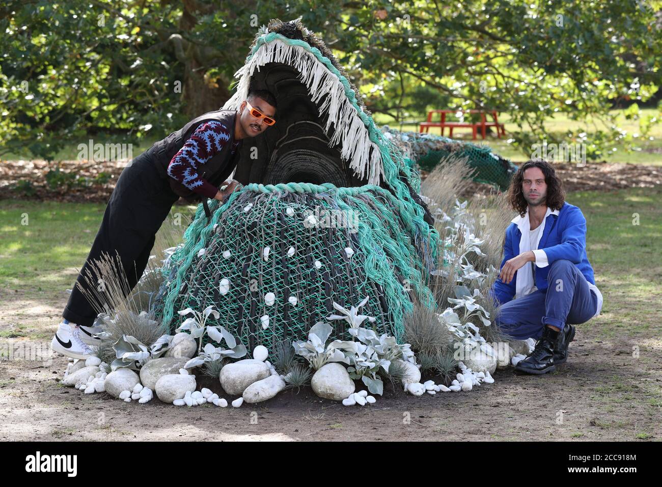 Die Künstler Ryan Lanji (links) und Andrew Whittle betrachten die botanische Skulptur eines Buckelwals, der vom Orangery Lawn auftaucht, die von den Gewinnern der Netflix Original Series, The Big Flower Fight, geschaffen wurde. Es wird bis September 18 im Rahmen des Travel the World at Kew Festivals in den Royal Botanic Gardens in London gezeigt. Stockfoto