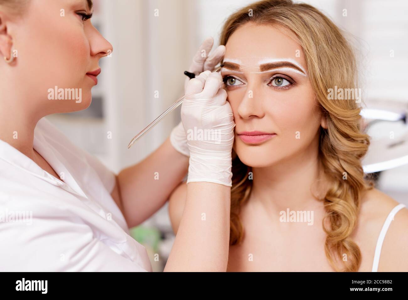 Make-up und Beauty-Konzept - Nahaufnahme von Kosmetologen Augenbrauen malen im Beauty Studio Stockfoto