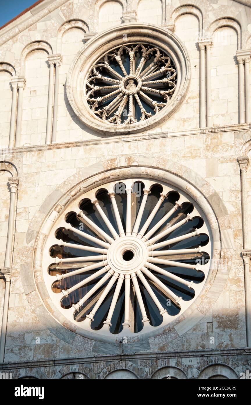 Detail von zwei Rosenfenstern (das Rosenfenster oben ist gotisch und das untere ist romanisch) der Kathedrale von St. Anastasia in Zadar, Kroatien Stockfoto