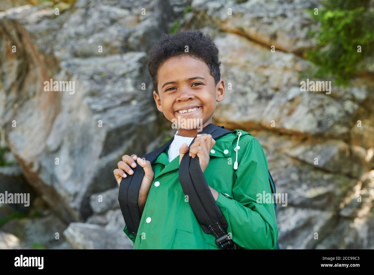 Porträt eines afrikanischen Jungen mit Rucksack hinter seinem Rücken lächelnd Bei der Kamera im Freien stehen Stockfoto