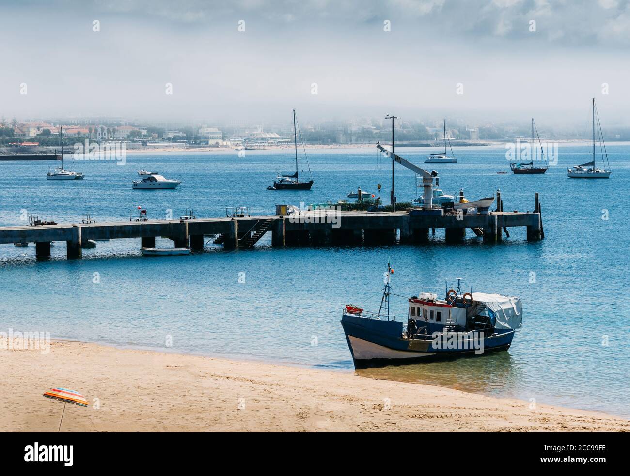 Hölzerne Fischerboot auf leerem Ribeira Strand in Cascais, Portugal mit landschaftlicher Hintergrund festgemacht Stockfoto