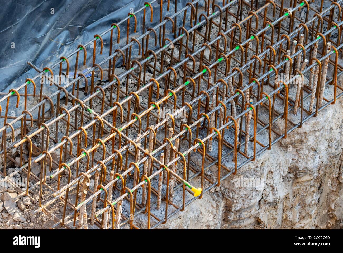 Industrielle Rebars für die Verstärkung während des Aufwickelungsprozesses. Rostiger Stahl mit Gewindestangen auf Beton auf der Baustelle. Overhead Stockfoto