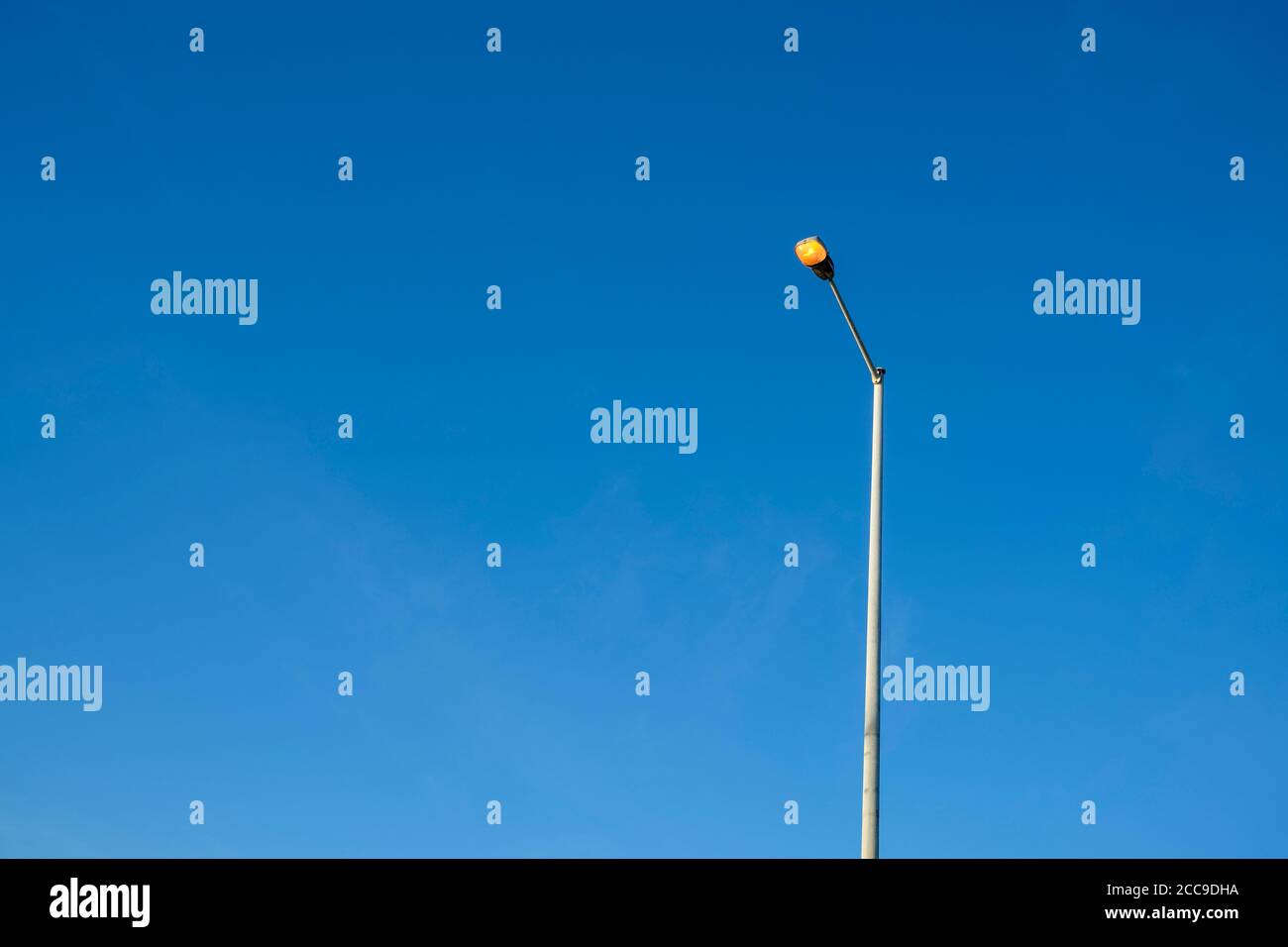 Eingeschaltete Straßenbeleuchtung gegen einen klaren blauen Himmel Stockfoto