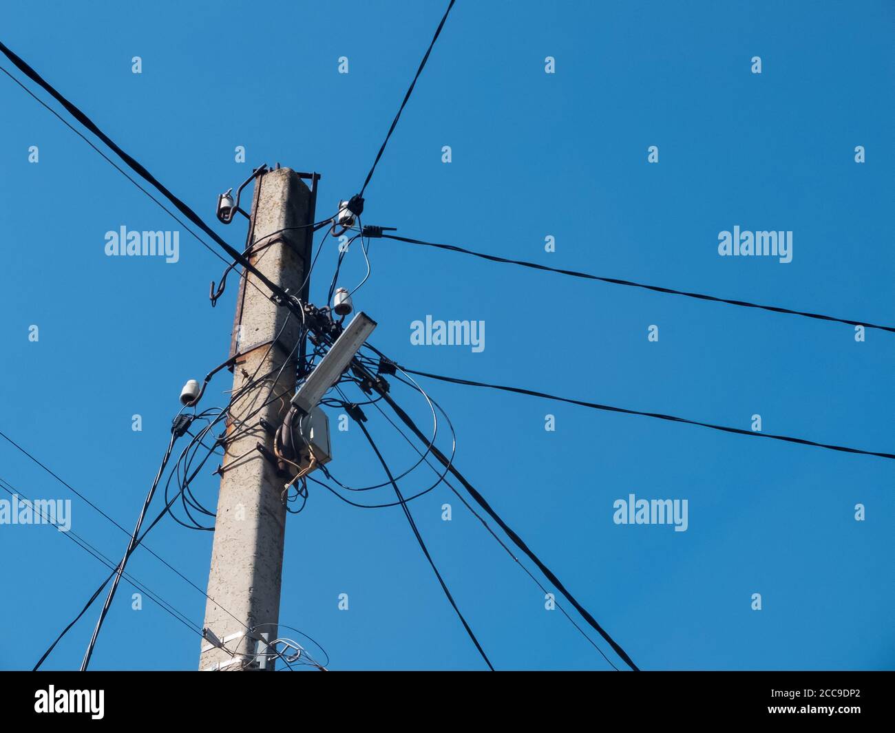 Betonmast mit Laterne und vielen elektrischen Drähten Stockfotografie
