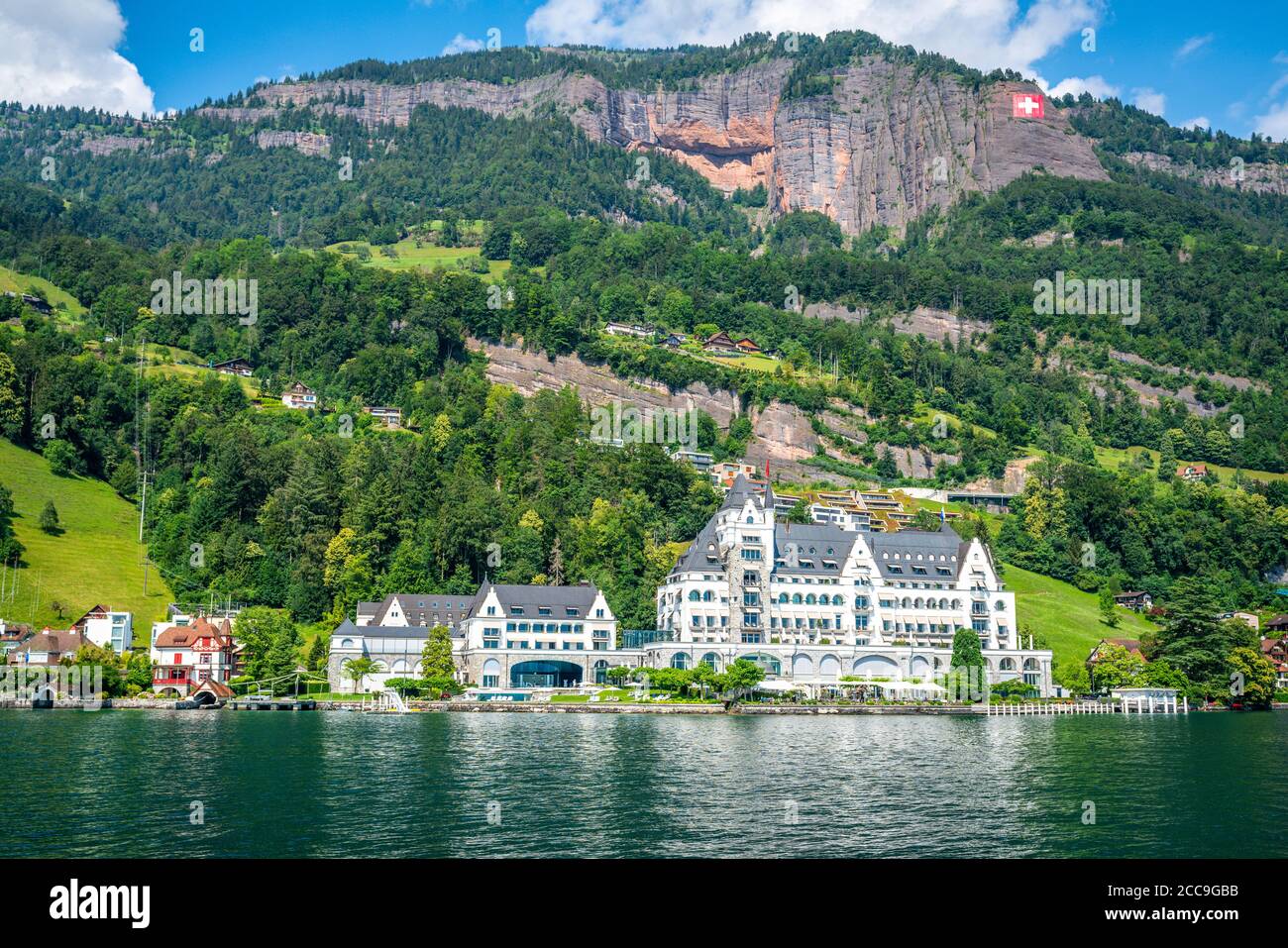 Vitznau Schweiz , 28. Juni 2020 : Luxury Park Hotel Vitznau vom Luzerner See und riesiger Schweizer Flagge an den Bergen in der Schweiz Stockfoto