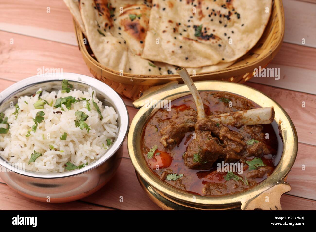 Hammelcurry serviert mit Naan oder Brot und Jeera-Reis auf Holzhintergrund. Stockfoto