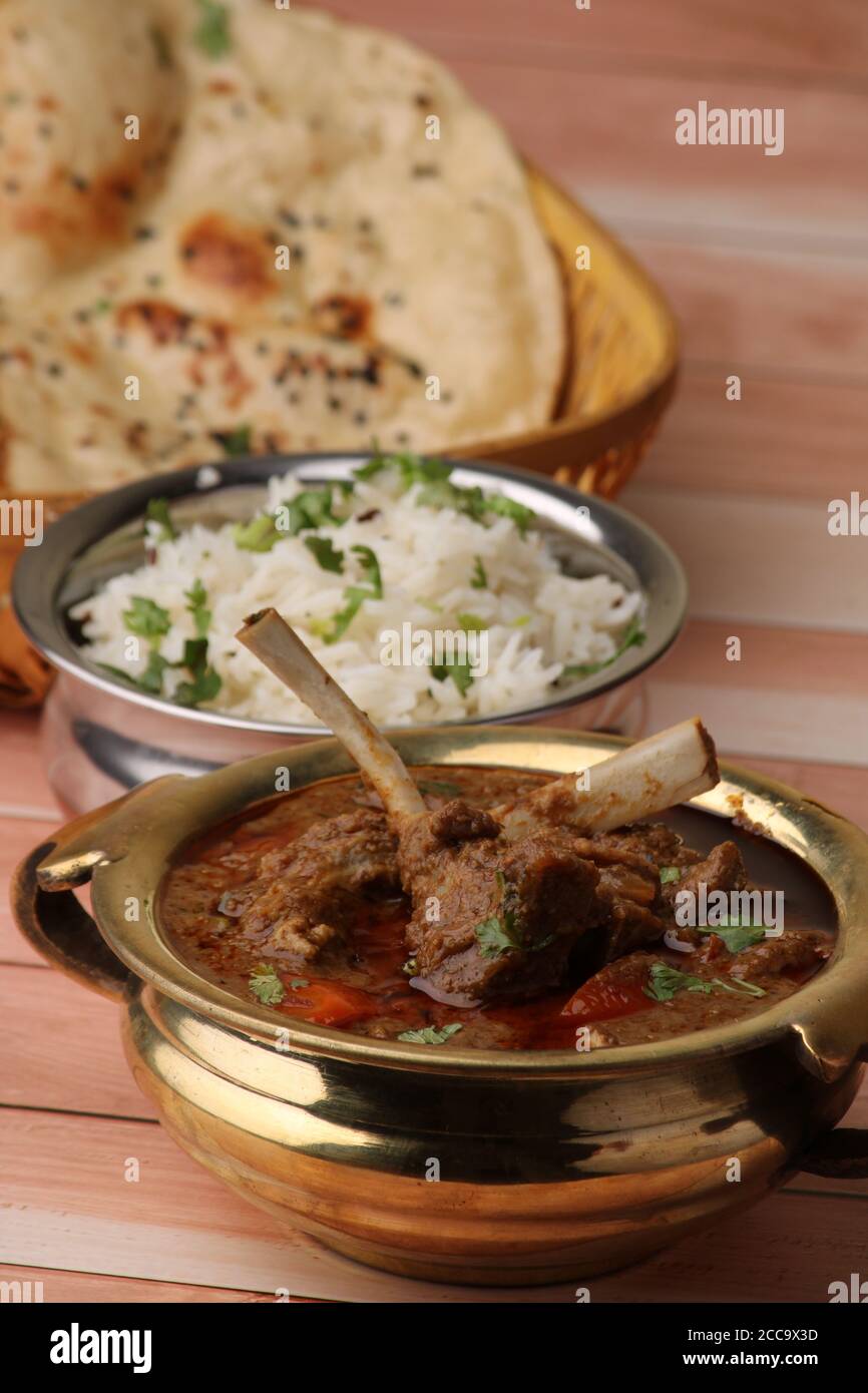 Hammelcurry serviert mit Naan oder Brot und Jeera-Reis auf Holzhintergrund. Stockfoto