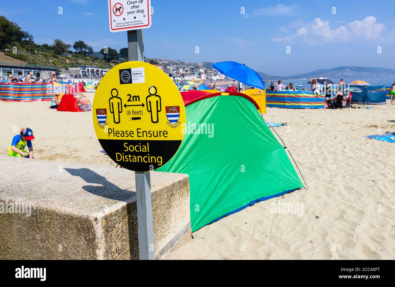 Am Strand anmelden: Bitte sorgen Sie für soziale Distanzierung, bei Lyme Regis, einem beliebten Badeort an der Jurassic Coast in Dorset, SW England Stockfoto