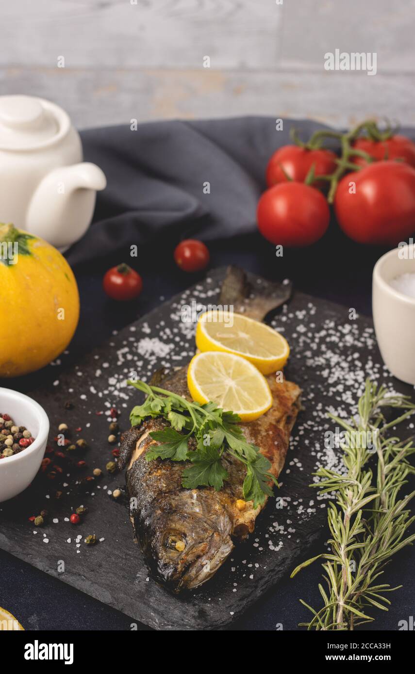 Gegrillte Forelle mit Olivenöl, Petersilie, Pfeffer, Salz und Zitrone auf den dunklen Hintergrund gelegt. Gesunde Ernährung und Diät-Konzept. Bereit zum Essen. Stockfoto