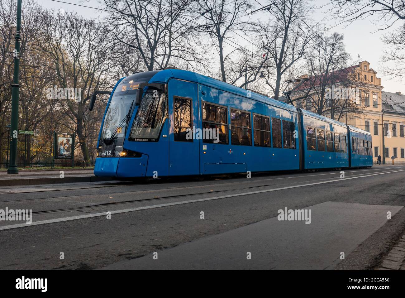 Eine moderne Straßenbahn fährt an einem Park im Zentrum von Krakau vorbei In Polen Stockfoto