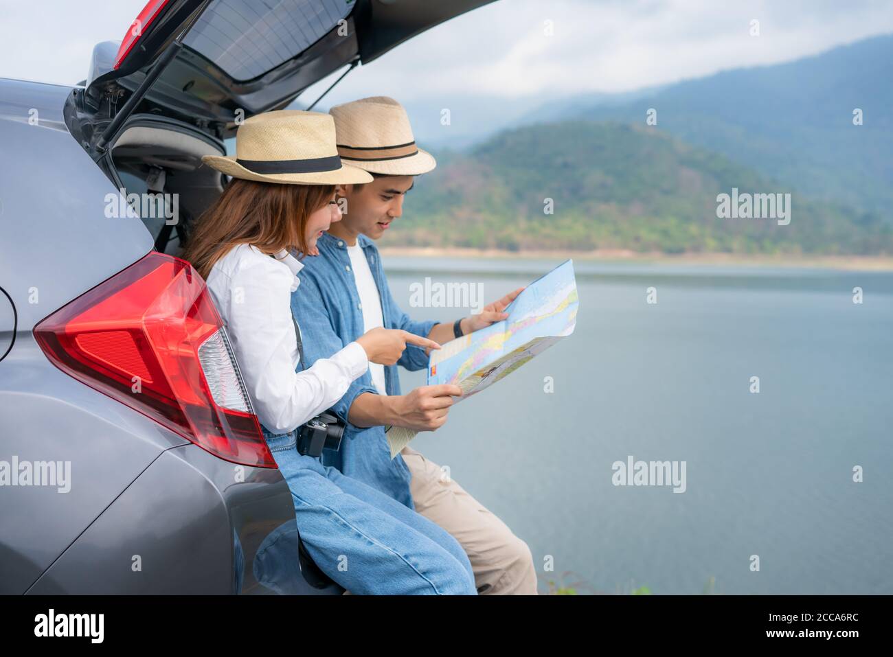 Portrait von asiatischen Paar sitzen im Auto mit Mann und Frau suchen schöne Landschaft und halten Karten während Urlaub zusammen im Urlaub. Happy roma Stockfoto