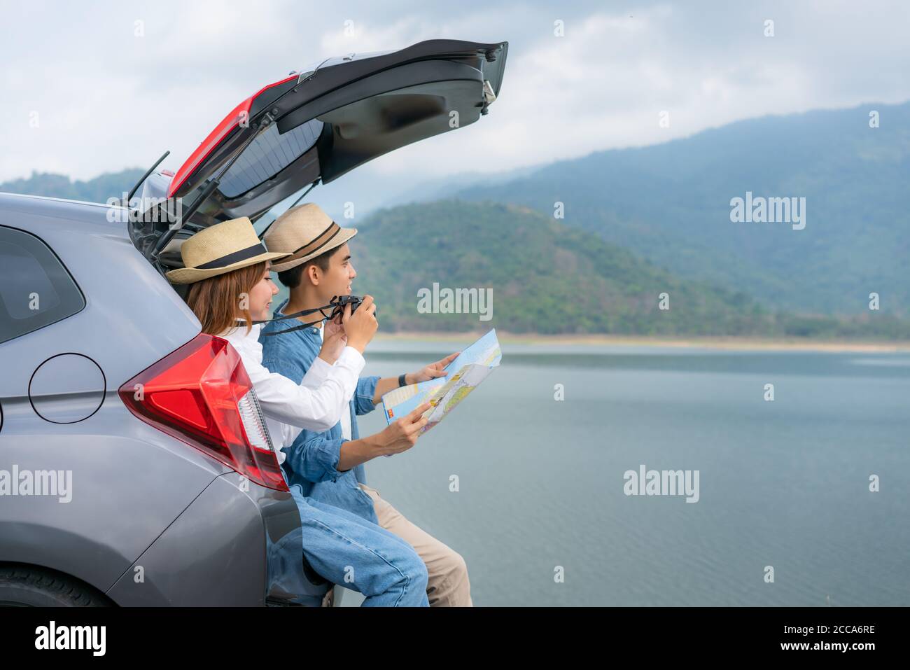 Portrait von asiatischen Paar sitzt im Auto mit Mann halten Karten und Frau, die ein Foto schöne Landschaft mit der Kamera Während Urlaub zusammen in holida Stockfoto