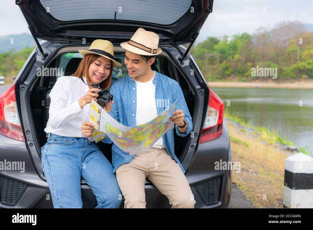Portrait von asiatischen Paar sitzen im Auto mit Mann und Frau suchen Foto in der Kamera und halten Karten während Urlaub zusammen im Urlaub. Viel Romantik Stockfoto