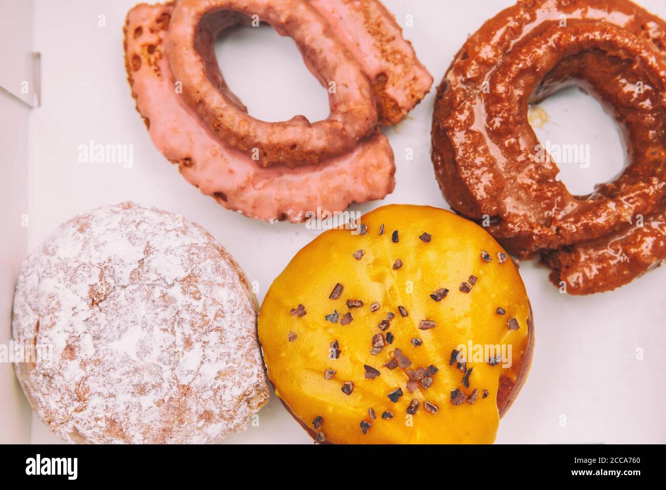 Donuts Box mit altmodischen Donuts aus Gebäck Bäckerei Café. Boston Sahne Donut, Berry Gelee gefüllt berliner, Himbeer glasiert Kruller gebraten Stockfoto