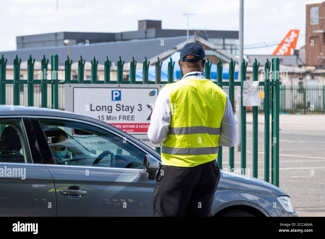 Eine Person in einem Auto, die in ein COVID-19 Coronavirus Testzentrum auf dem Langzeitparkplatz am Flughafen London Southend einfährt, mit easyJet-Flugzeug-Heck. Verfolgen Stockfoto