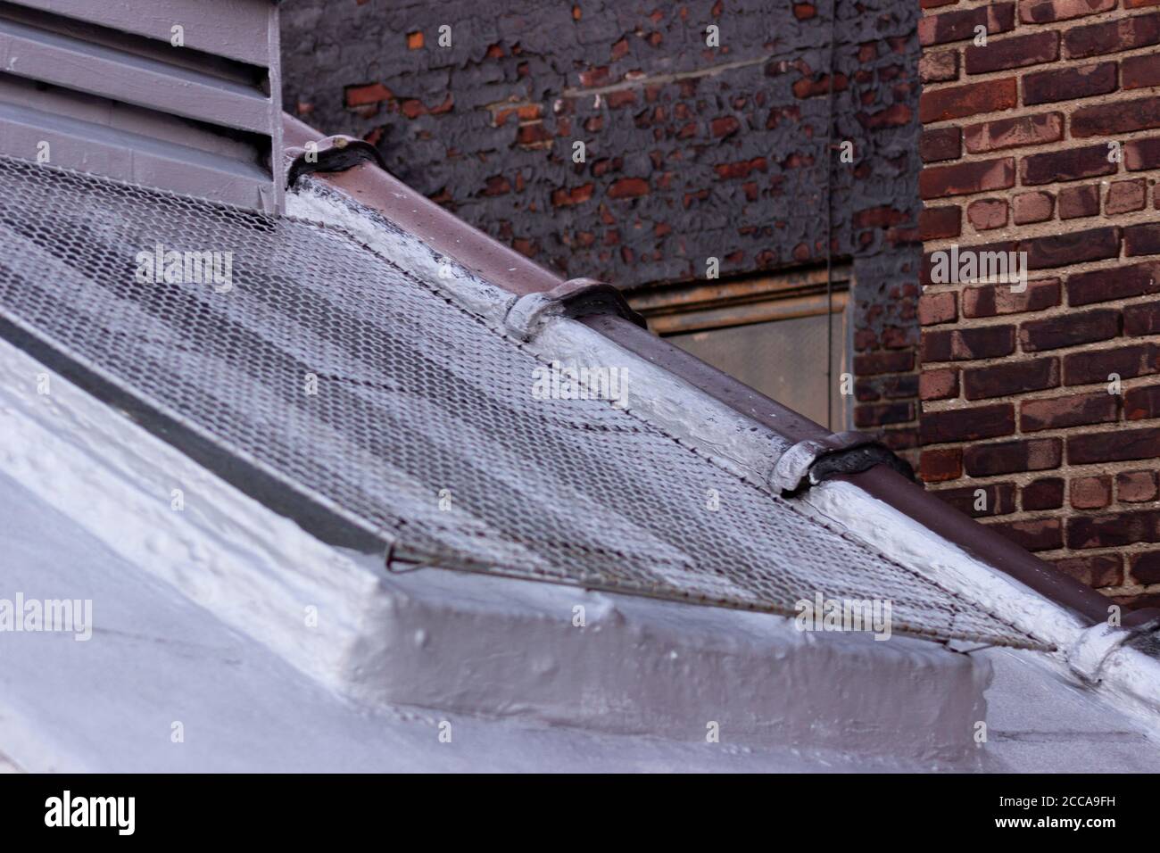 Treppenhaus Luftschacht Außenfenster mit Vogel-obstructing Bildschirm bedeckt, mit gemaltem Ziegel und einfachen roten Ziegel im Hintergrund Stockfoto