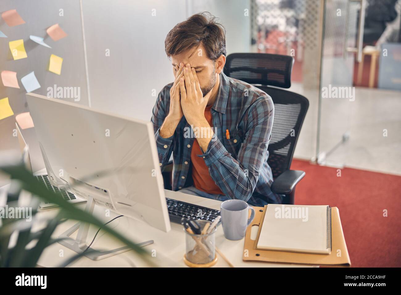 Müde junge Mann arbeitet in modernen Büro Stockfoto