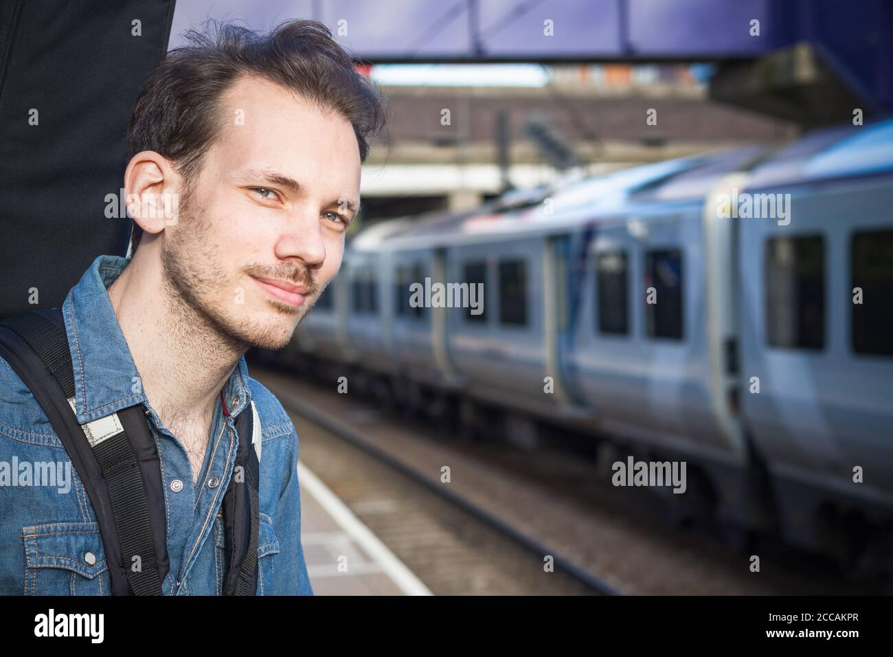 Portrait eines kaukasischen jungen Mannes, der auf den Zug wartet Plattform Stockfoto
