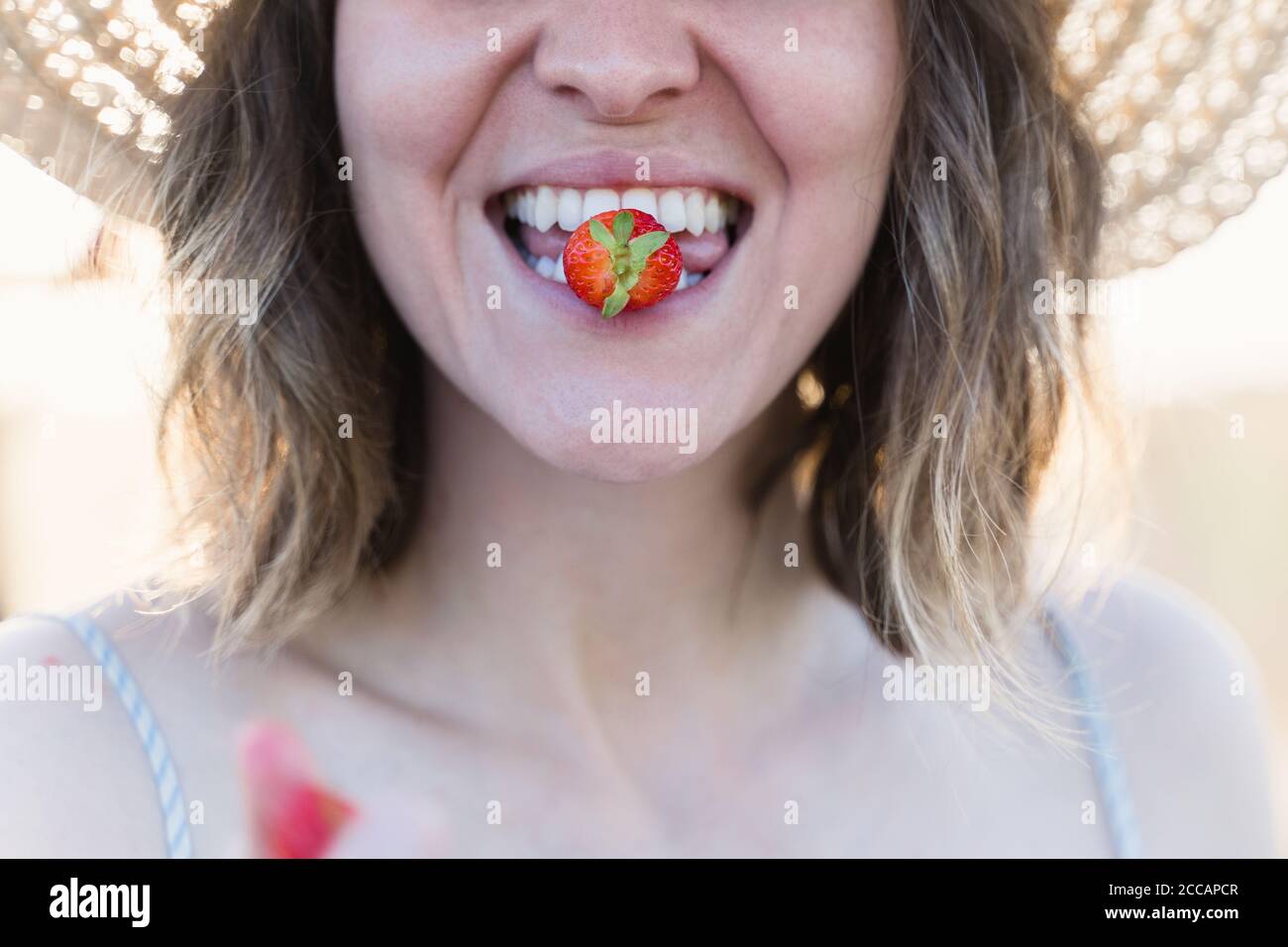 Junge Bäuerin beißt eine frisch reife Erdbeere Stockfoto Junge Bäuerin beißt eine frisch reife Erdbeere Stockfoto