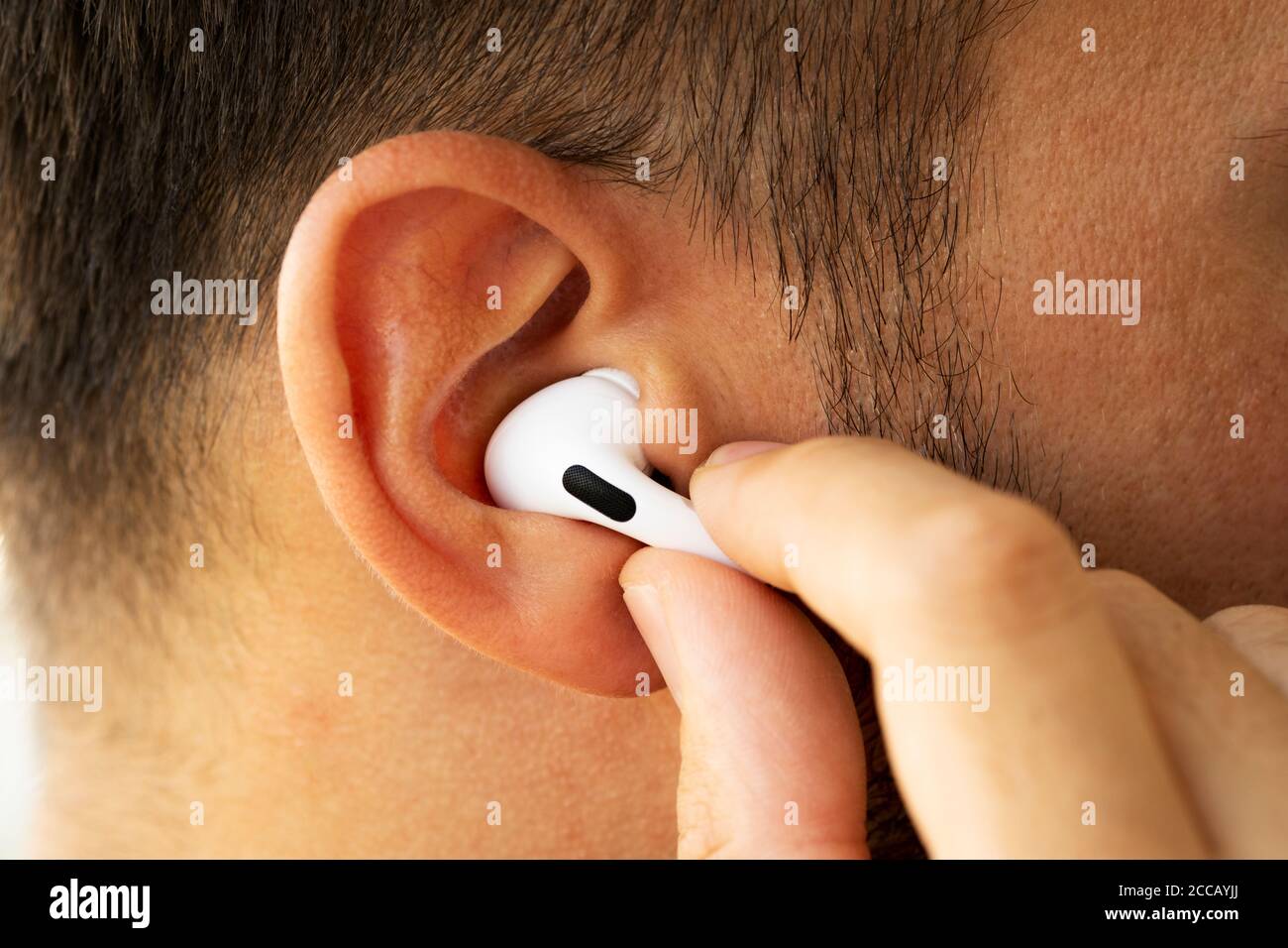 Izmir, Türkei - 7. August 2020: Nahaufnahme von weißen Apple AirPods auf  dem Ohr eines Mannes. Halten Sie ihn mit einer Hand und drücken Sie die  Taste Stockfotografie - Alamy
