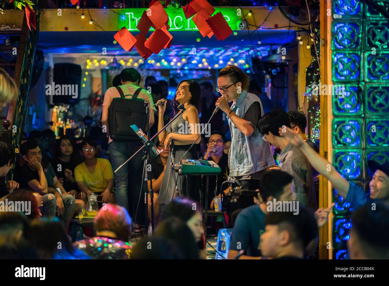 Ho Chi Minh Stadt, Vietnam - 29. April 2018: Eine Frau singt mit einem Mikrofon zur Begleitung einer von Menschenmassen umgebenen Musikband in der Bui Vien Straße. Stockfoto