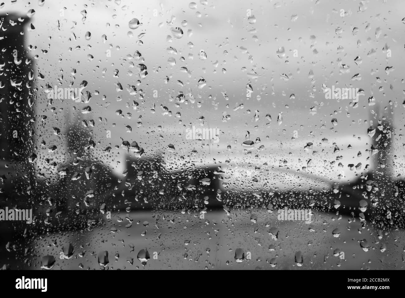 Regen auf dem feuchten Glas der Media City Fußgängerbrücke über den Manchester Ship Canal, Salford Quays, Manchester, England, UK: Schwarz-weiß Version Stockfoto