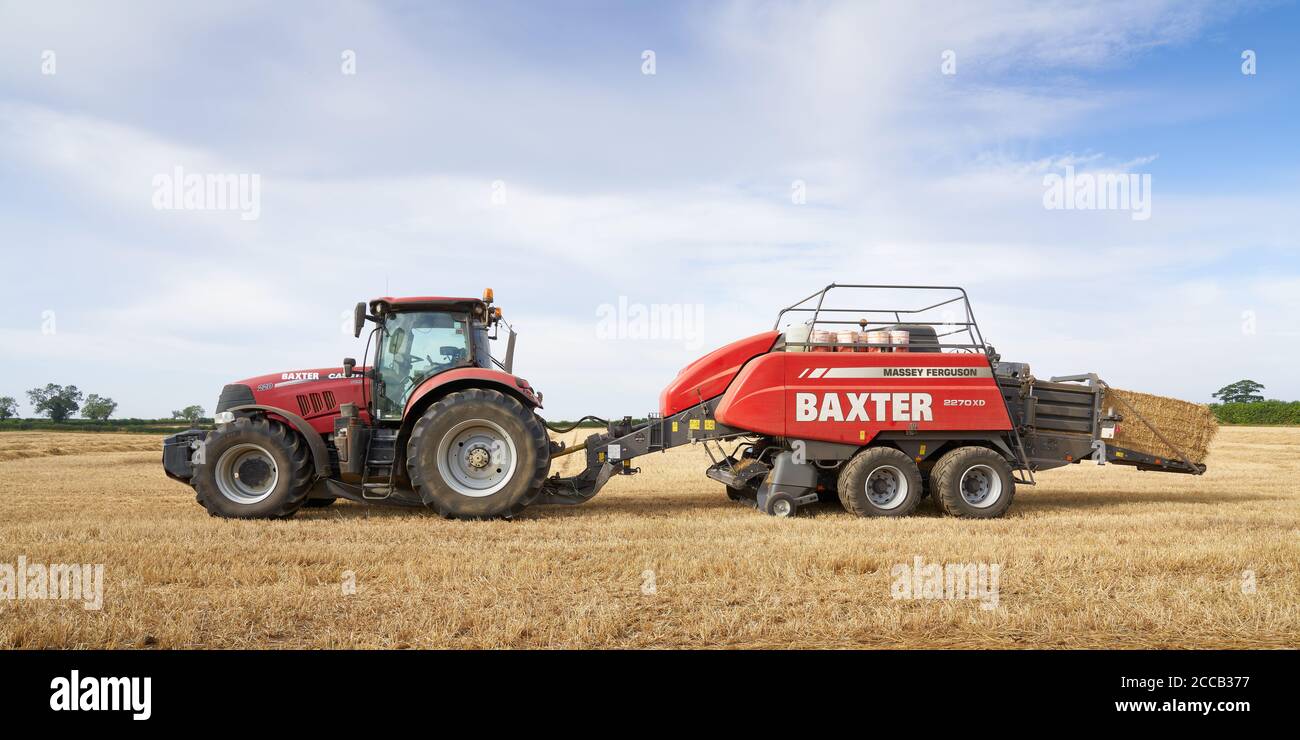 Case Puma 220 Traktor Ballenpressen in einem Lincolnshire Feld mit Eine große Massey Ferguson 2270XD Ballenpresse an einem August Sommer Abend Stockfoto