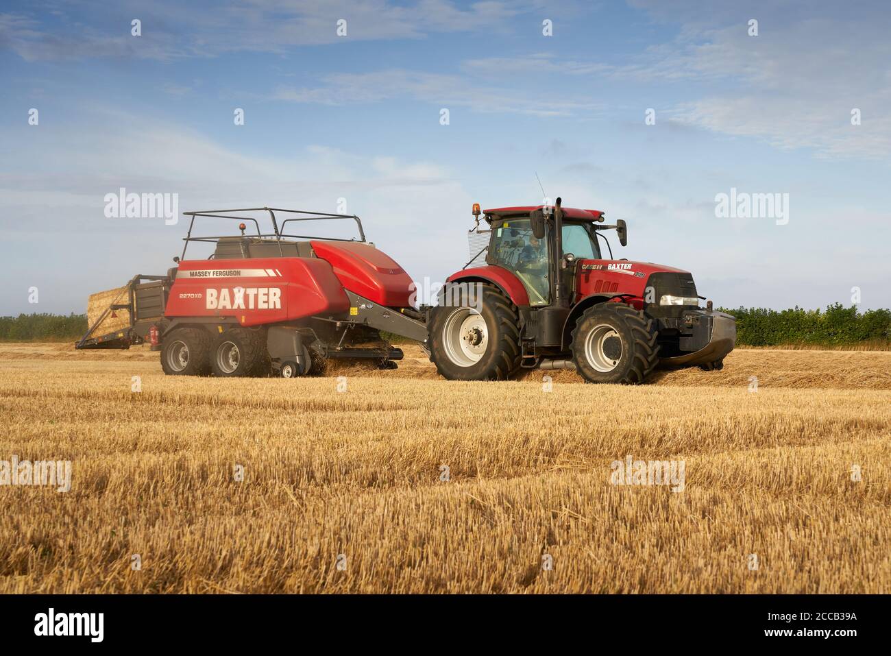 Case Puma 220 Traktor Ballenpressen in einem Lincolnshire Feld mit Eine große Massey Ferguson 2270XD Ballenpresse an einem August Sommer Abend Stockfoto
